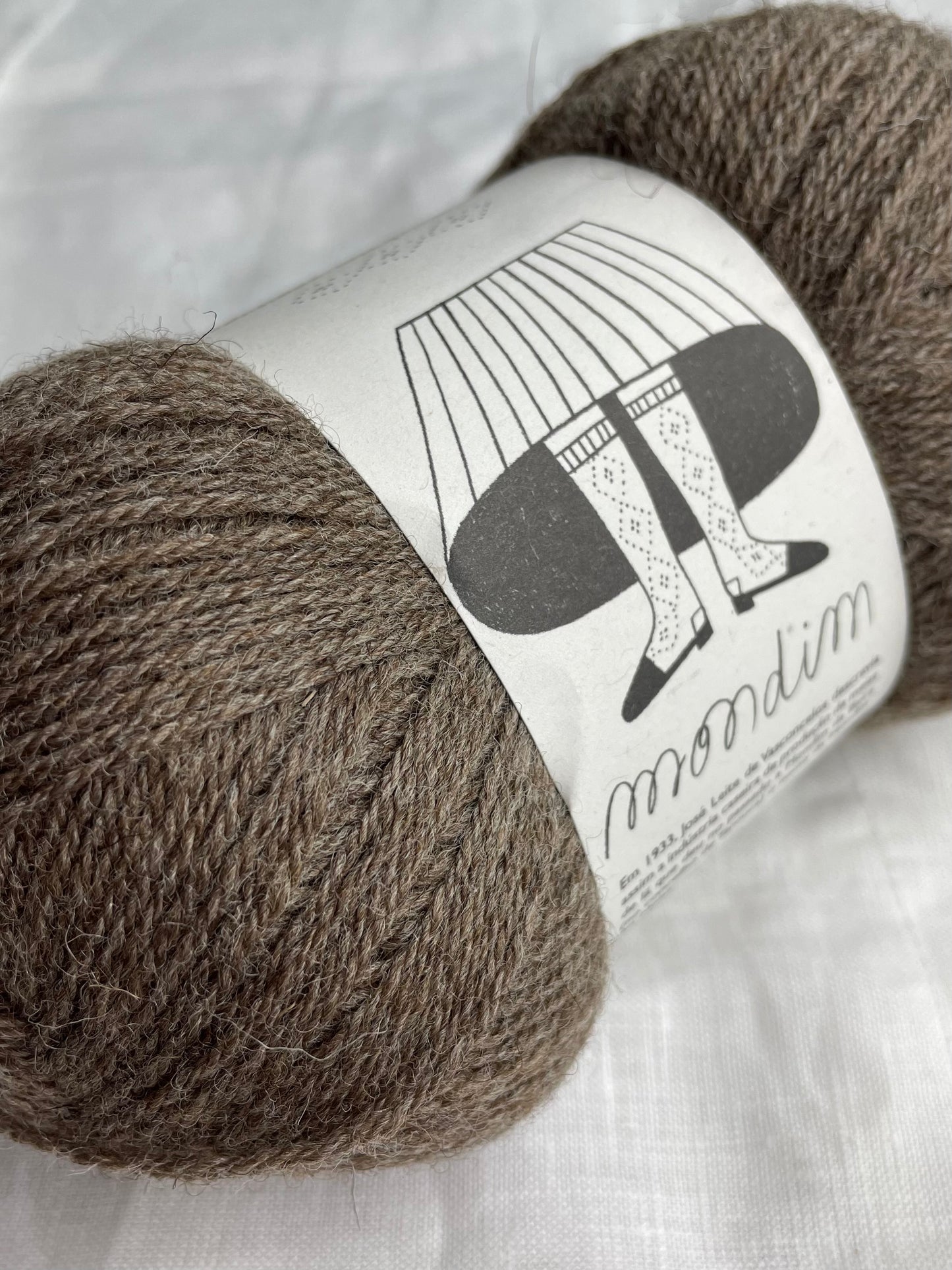 One ball of Mondim Sock Yarn in a mid toned grey colour on a white linen background.