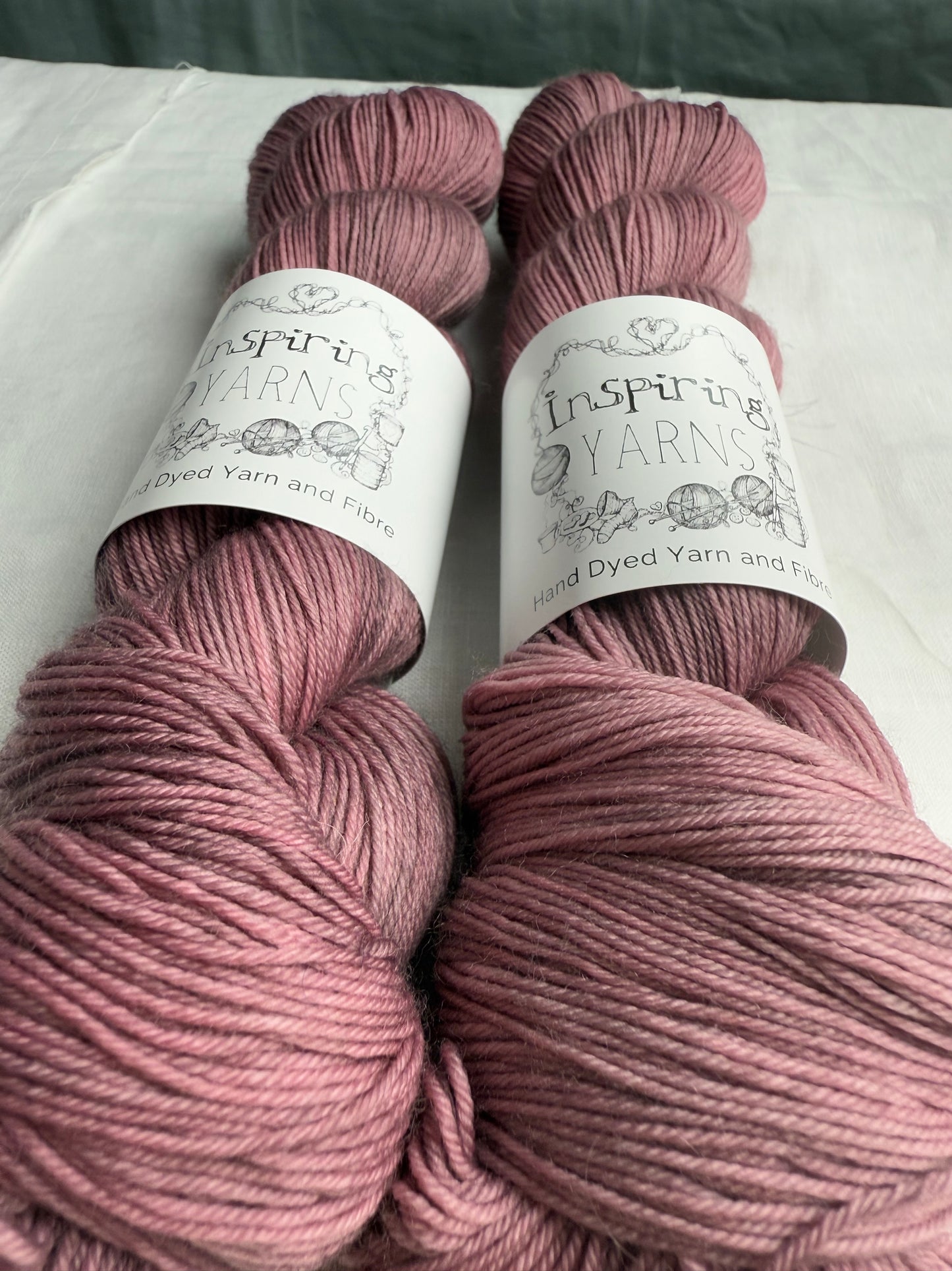 up close of two grey mauve yarn on white background with inspiring yarns labels.