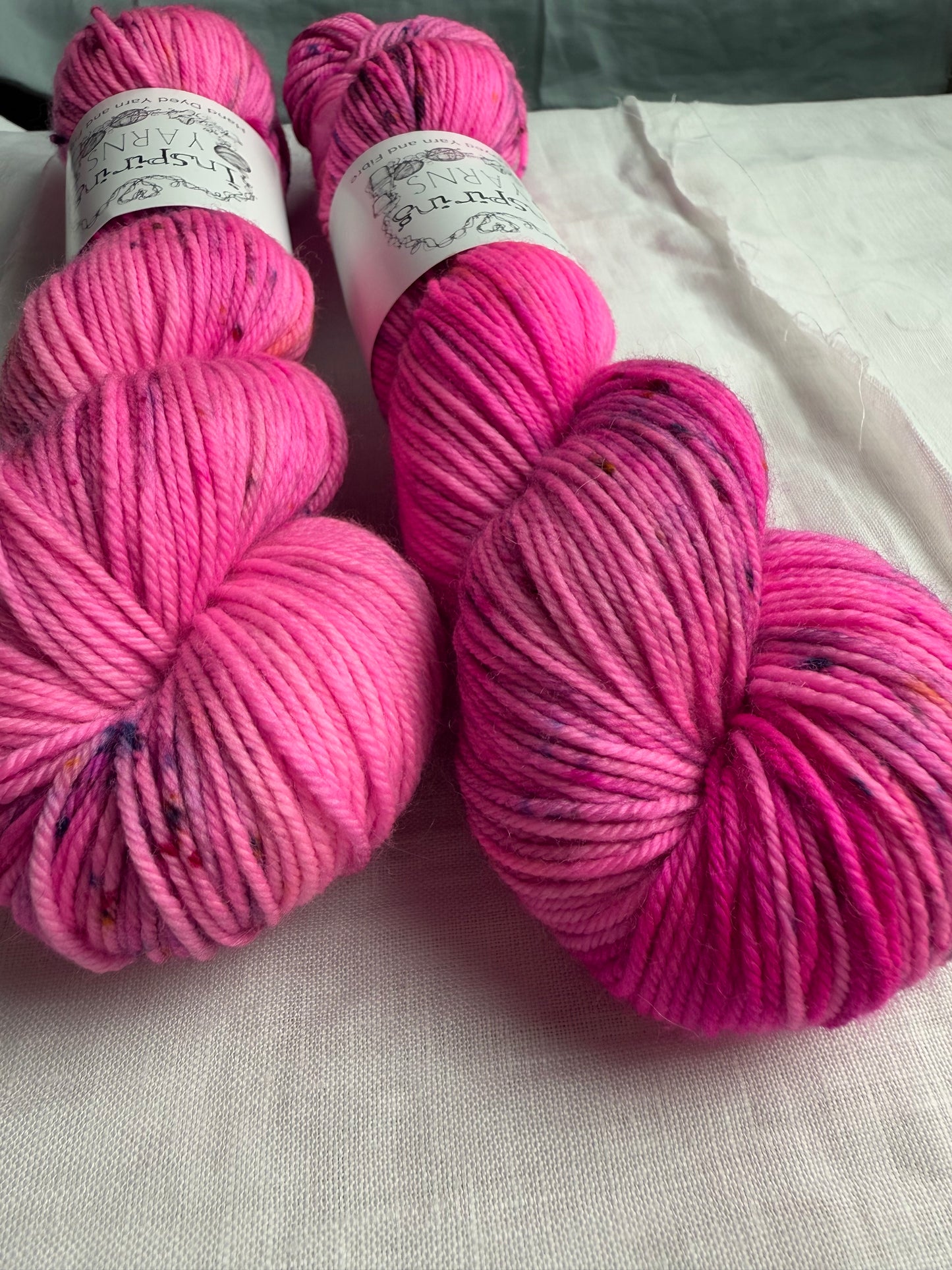 up close of neon pink yarn with speckles on a white background.