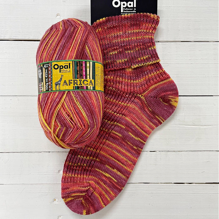 Opal Africa yarn ball and sock in reds and yellow on a wooden surface