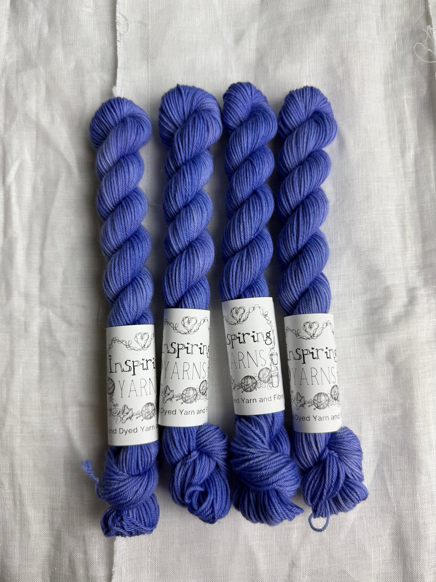 four mini skeins of blue merino wool with inspiring yarns black and white labels .