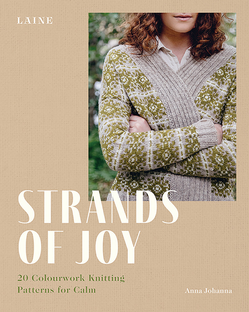 Book cover of 'Strands of Joy' by Laine with a person wearing a knitted sweater.
