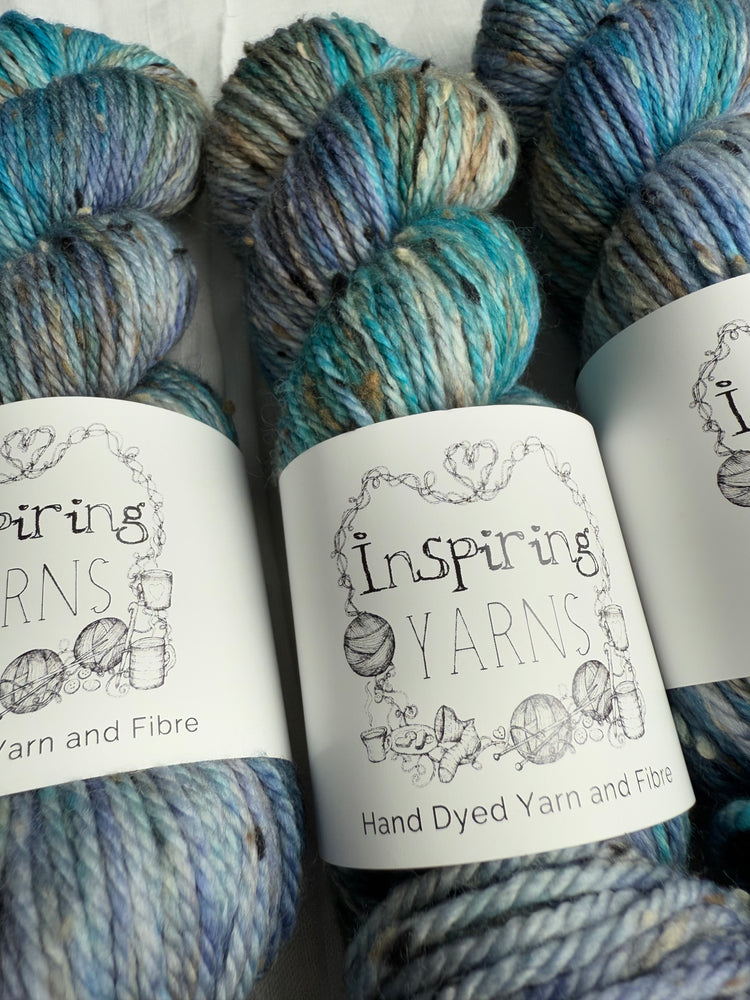 Image shows 3 skeins of Donegal Aran dyed in a mix of blues and brown and labelled Inspiring Yarns. 