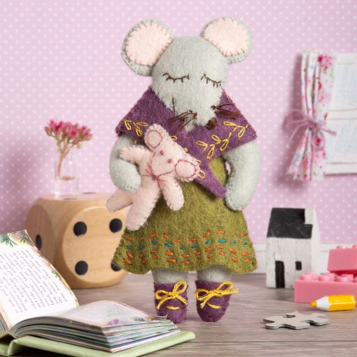 Image shows an example of a Corinne La Pierre mini embroidery kit,  hand stitched and embroidered felt mouse decoration dressed in shawl, skirt and shoes and holding a teddy.