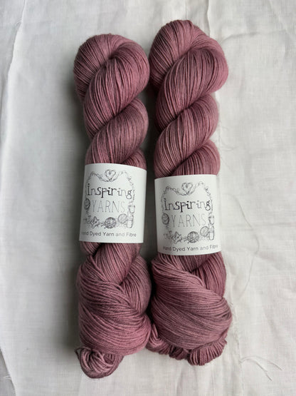 Two skeins of grey mauve grey yarn with inspiring yarns label on a white background.
