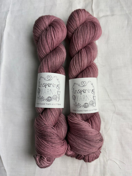 Two skeins of grey mauve grey yarn with inspiring yarns label on a white background.