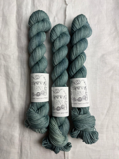 Three skeins of teal yarn with 'Inspiring Yarns' labels on a white background