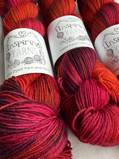 Three skeins of red variegated yarn labelled Inspiring Yarns on a white background