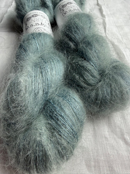 two skeins of mohair silk lace yarn in a pale teal colour and labelled Inspiring Yarns on a white background