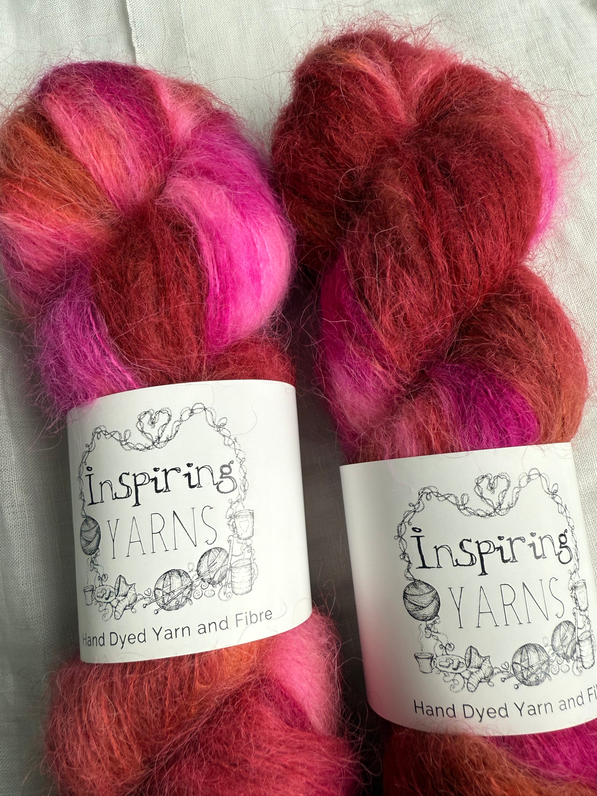 two skeins of pink and brown yarn up close with inspiring yarns labels on white background.