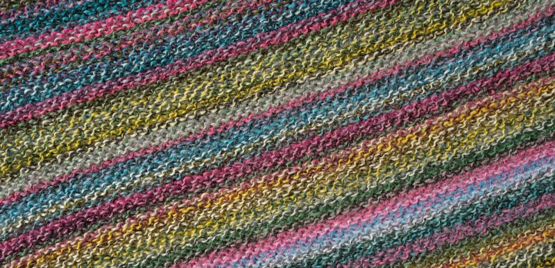 Image shows knitted swatch for  Schoppel Zauberball Crazy 4ply/sock.  The colour is 2389 Anniversary Party/Jubilaumsparty, with shades of yellow, blue, pink and mauve.