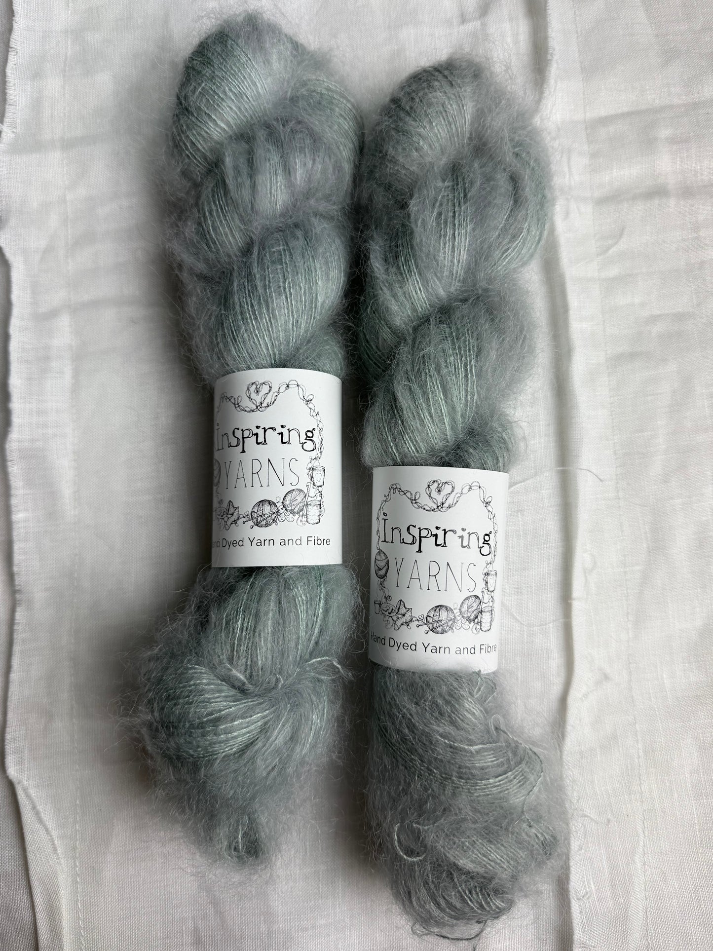 Two skeins of yarn with labels on a white fabric background