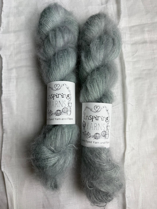 Two skeins of yarn with labels on a white fabric background