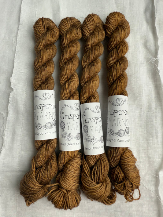 four skeins of light brown tonal yarn with inspiring yarns labels on a white background.