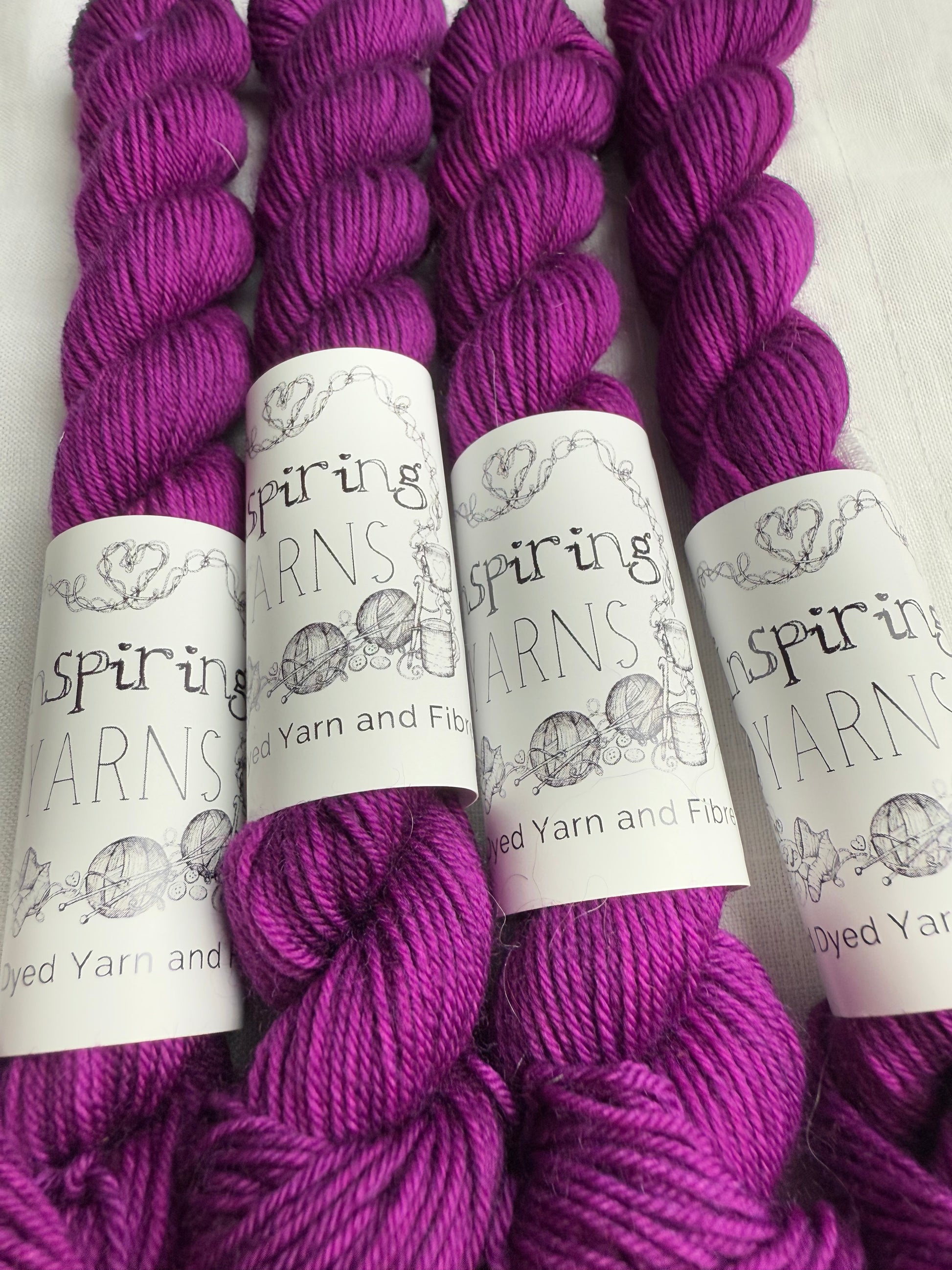 up close of fuchsia mini skeins on a white background with inspiring yarns labels.