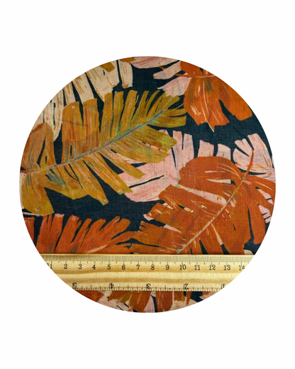 Del Mar design from Sunday Collection for Cloud9 Fabrics, a pattern of palm leaves in orange and pink on a dark blue background. A round swatch shown on a white background with a wooden ruler in centimeters for scale.