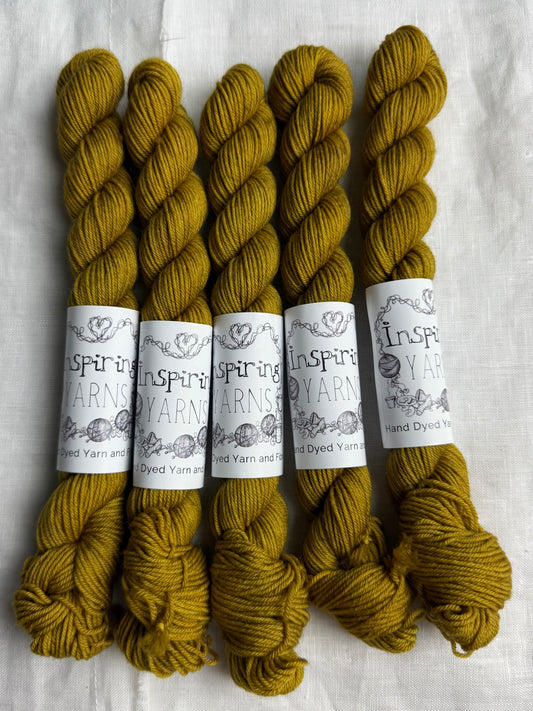 Five skeins of dark gold yarn with 'Inspiring Yarns' labels on a white background.