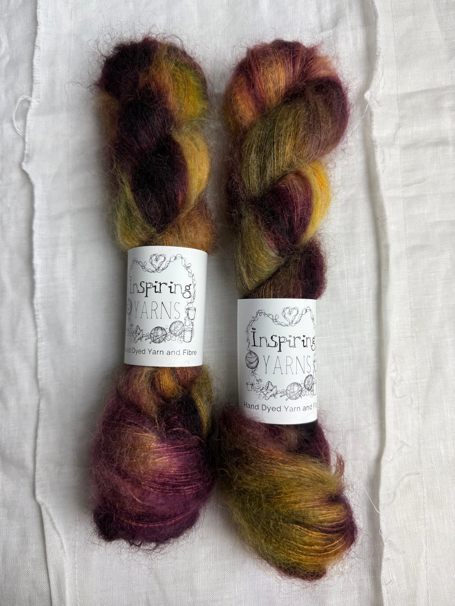 Two skeins of multicolored yarn with labels on a textured white background