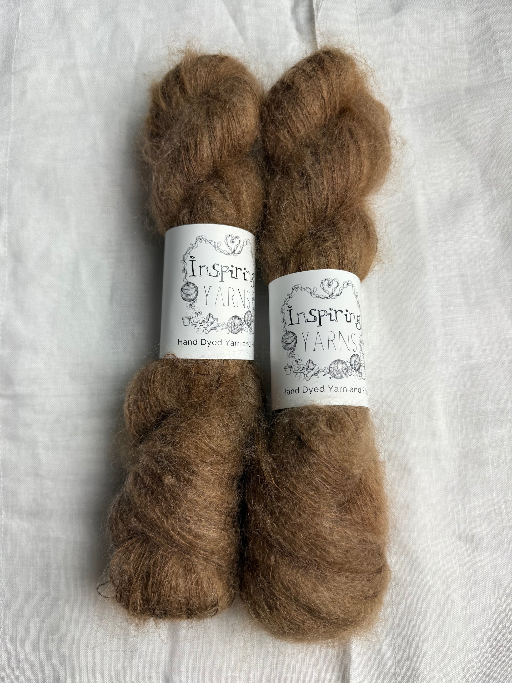 two skeins of a tonal light brown mohair with inspiring yarns label on white background.
