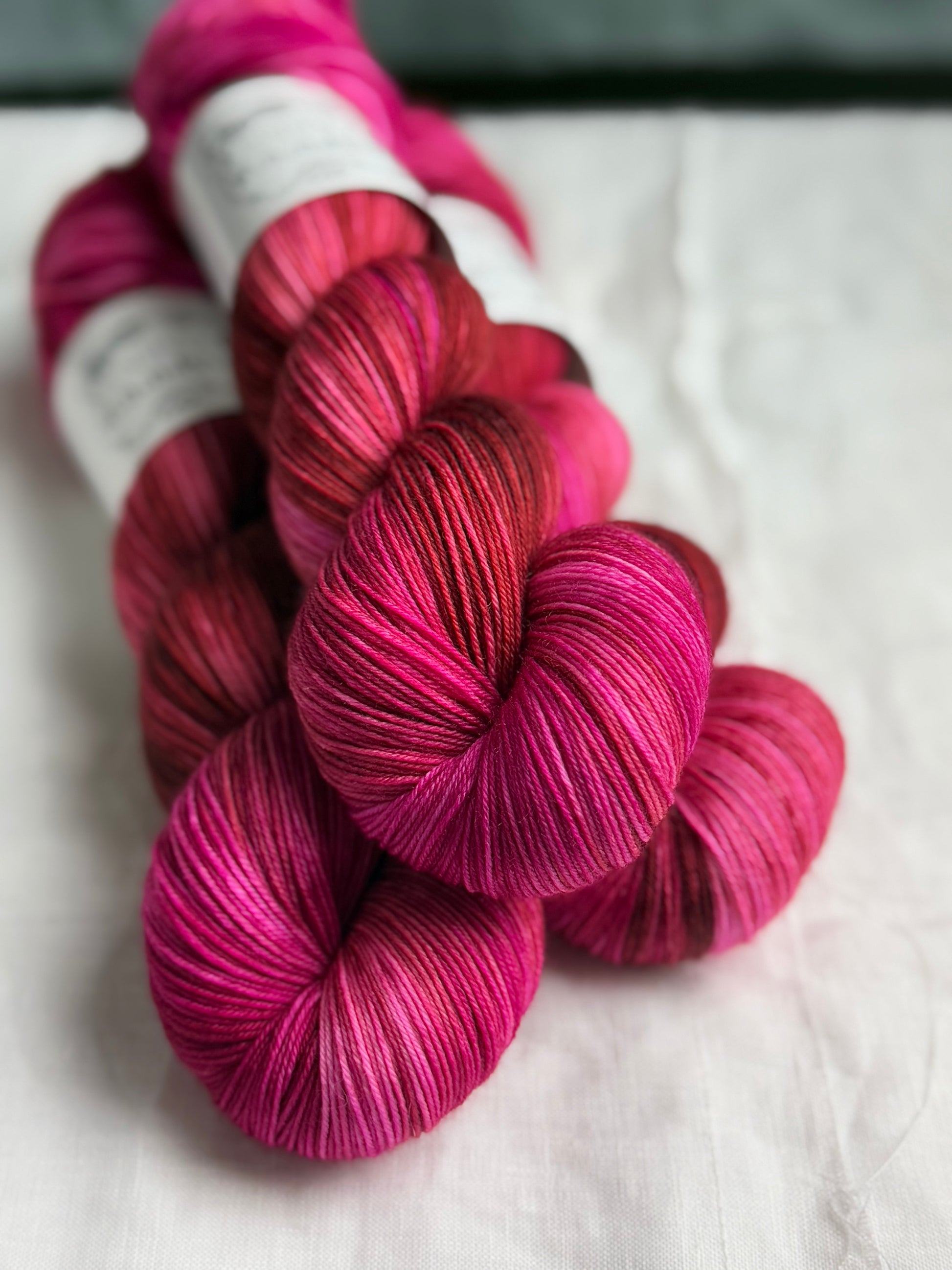 three skeins of pink and brown yarn stacked with labels out of view and a white background