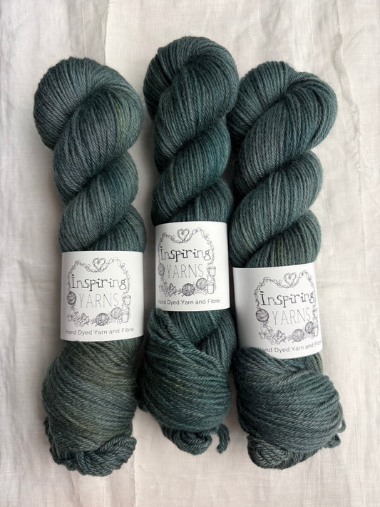 Three skeins of dark green tonal yarn labelled Inspiring Yarns on a white background