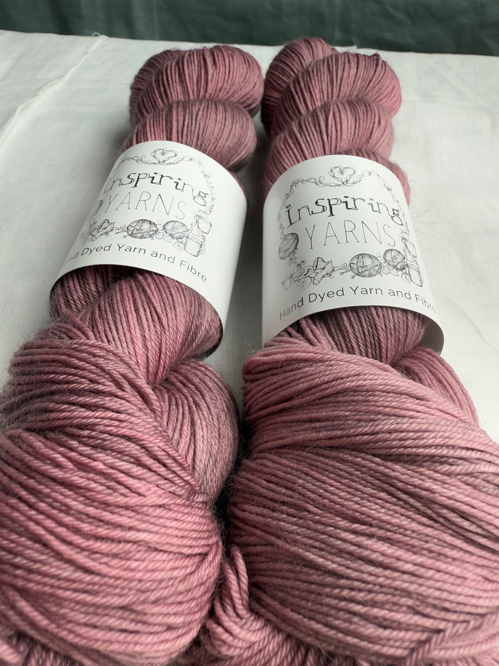 up close of two grey mauve yarn on white background with inspiring yarns labels.