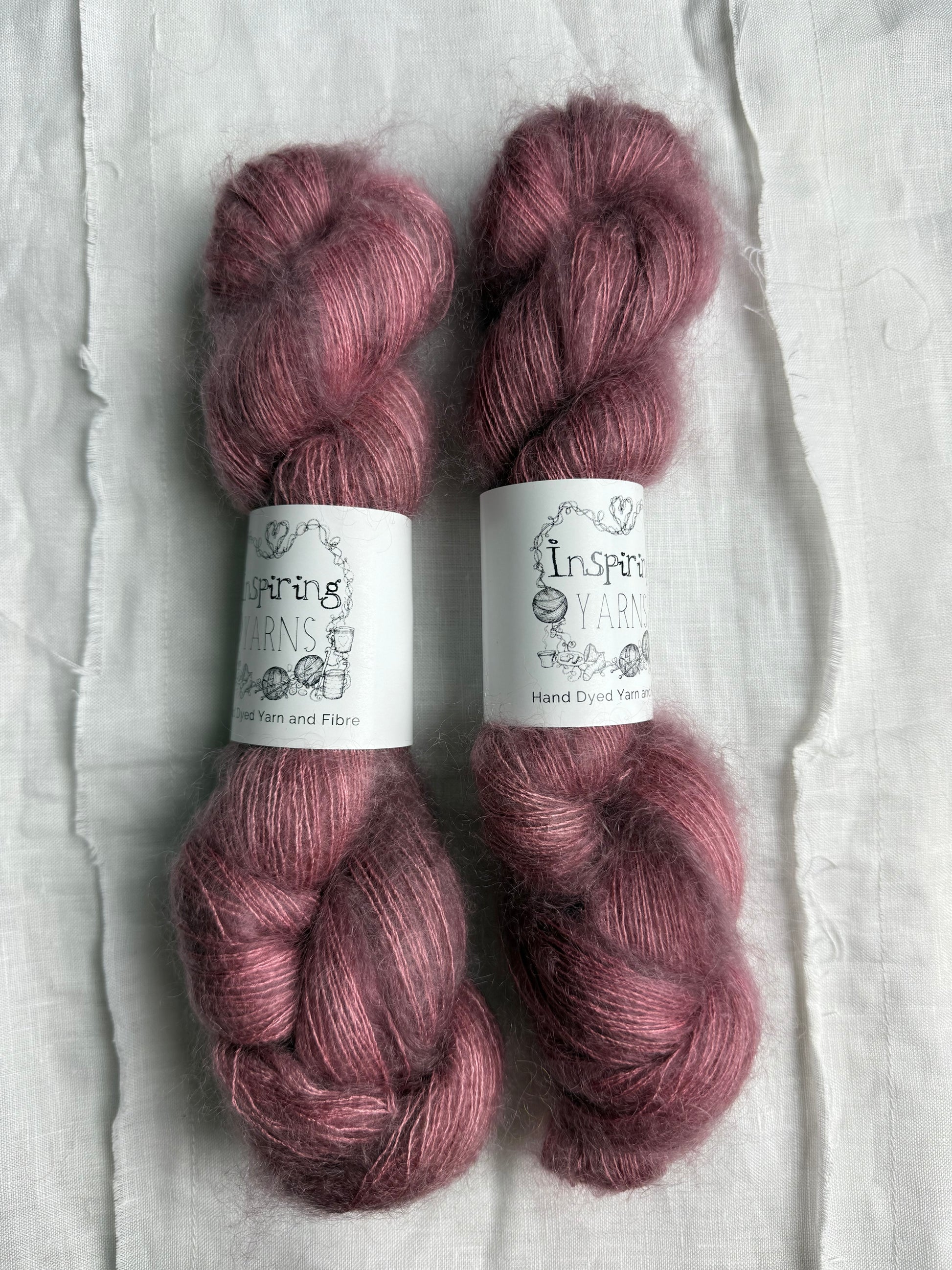 three skeins of dusty pink yarn with white inspiring yarns labels 