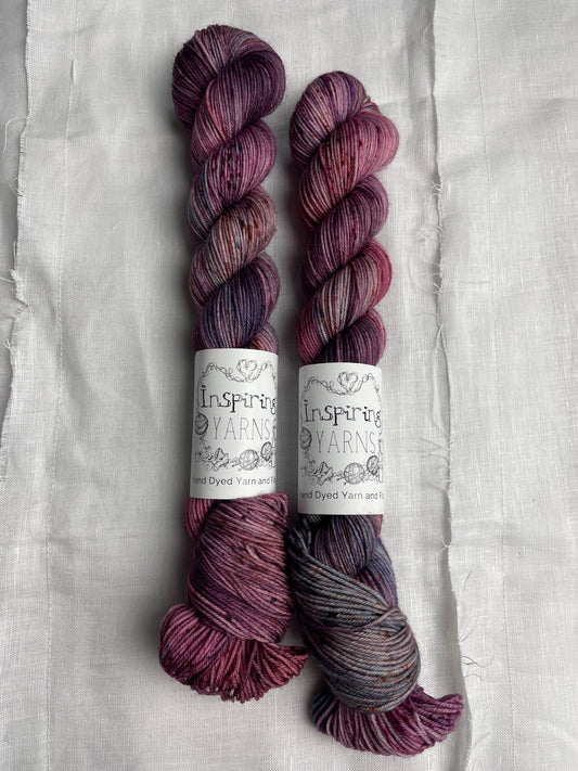 Two skeins of merino smooth sock in shades of pink and blue labelled Inspiring Yarns on a white linen background. 