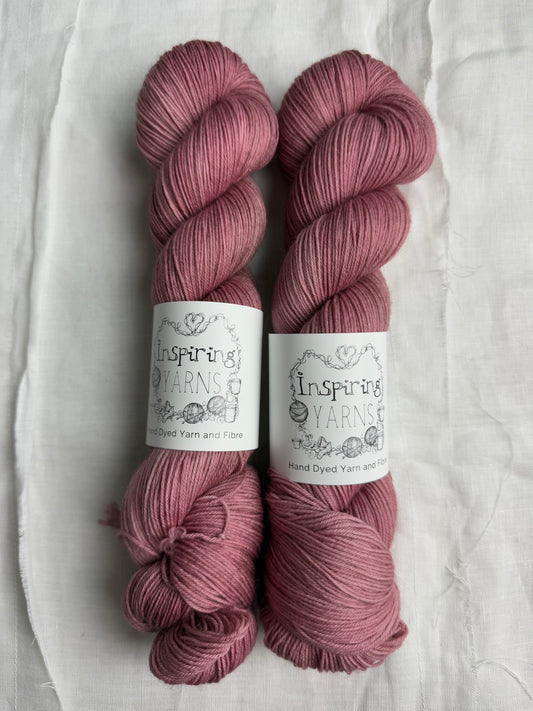 two skeins of light dusty pink yarn , with inspiring yarns label on white background.