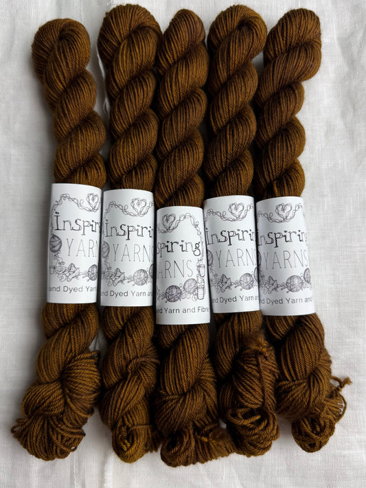 Five skeins of brown yarn with labels on a white background