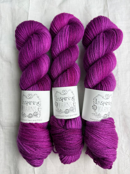 Three skeins of fuchsia tonal yarn labelled Inspiring Yarns on a white background