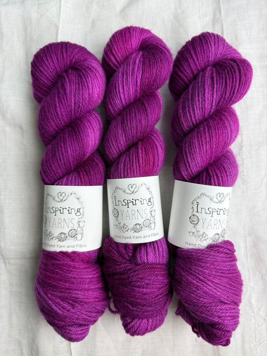 Three skeins of fuchsia tonal yarn labelled Inspiring Yarns on a white background