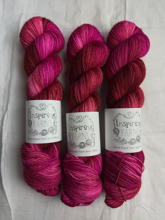 three skeins of pink and brown yarn with inspiring yarns labels on a white background 