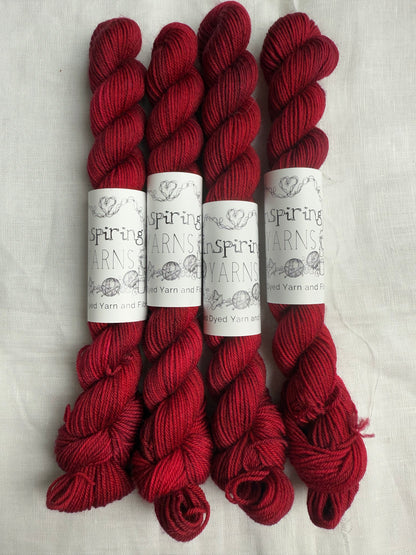 4 mini skeins of dark ruby red with inspiring yarns labels on white background.