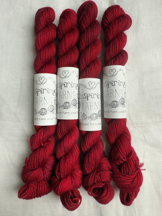 4 mini skeins of dark ruby red with inspiring yarns labels on white background.
