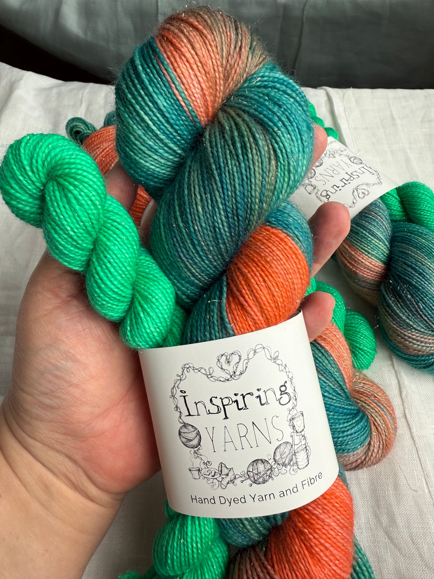 hand holding yarn sock set in peaches greens oranges and teal with a gentle gold stellina sparkle  