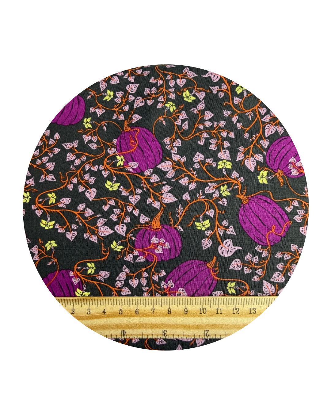 Round fabric swatch of Pumpkin Patch Deep, from the Spooky 'n' Witchy Collection by Art Gallery Fabric, a pattern of purple pumpkins and vines on a dark background with a wooden ruler in centimetres for scale, on a white background.