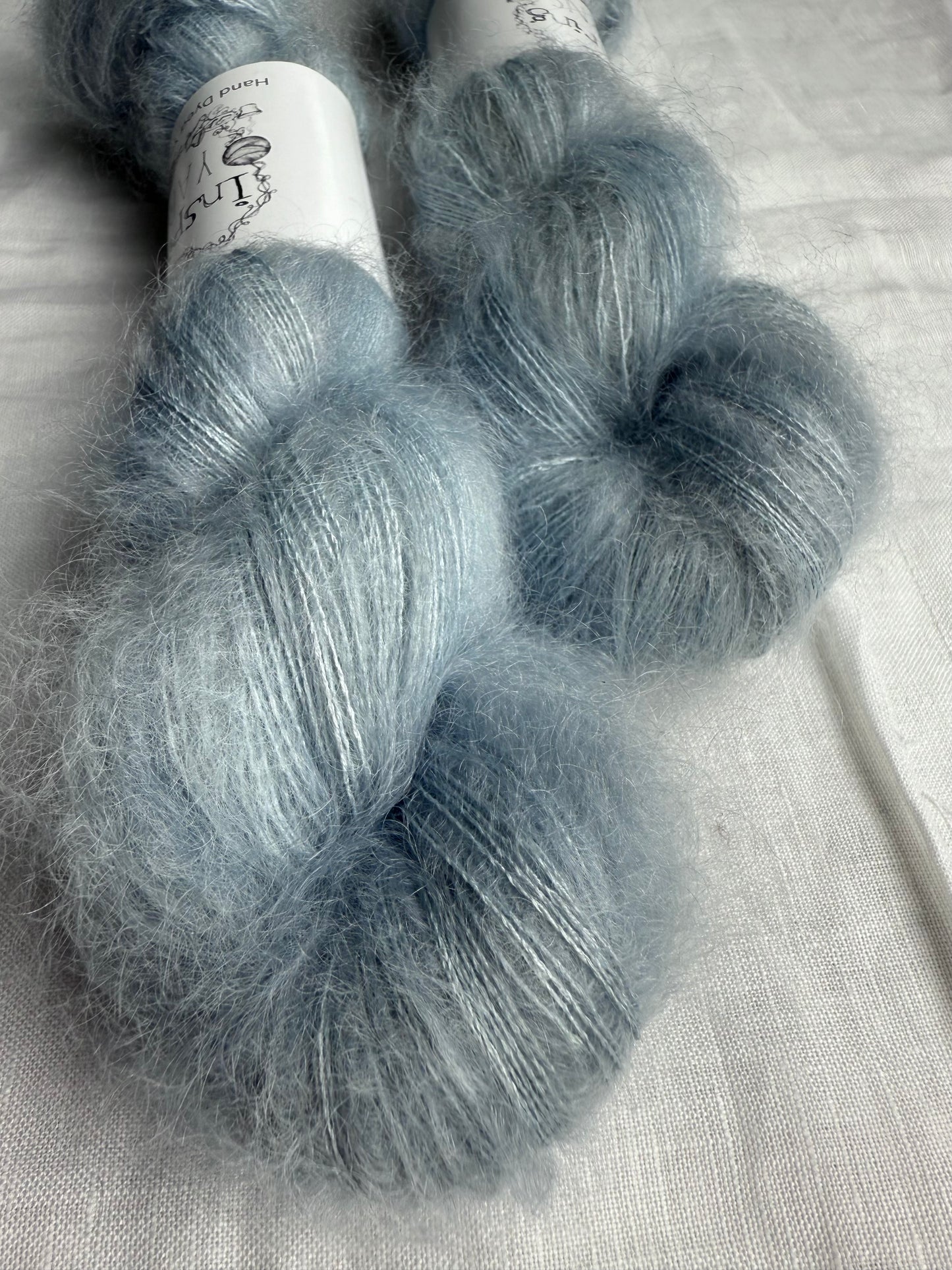 Two skeins of gray yarn on a light fabric background