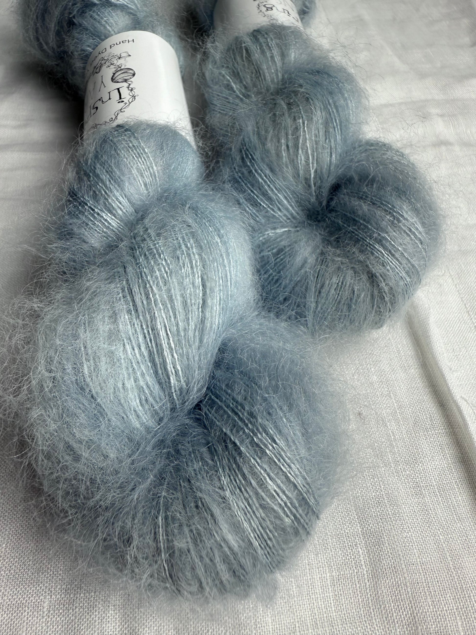 Two skeins of gray yarn on a light fabric background