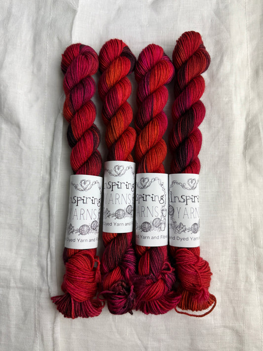 Four skeins of red variegated yarn labelled Inspiring Yarns on a white background