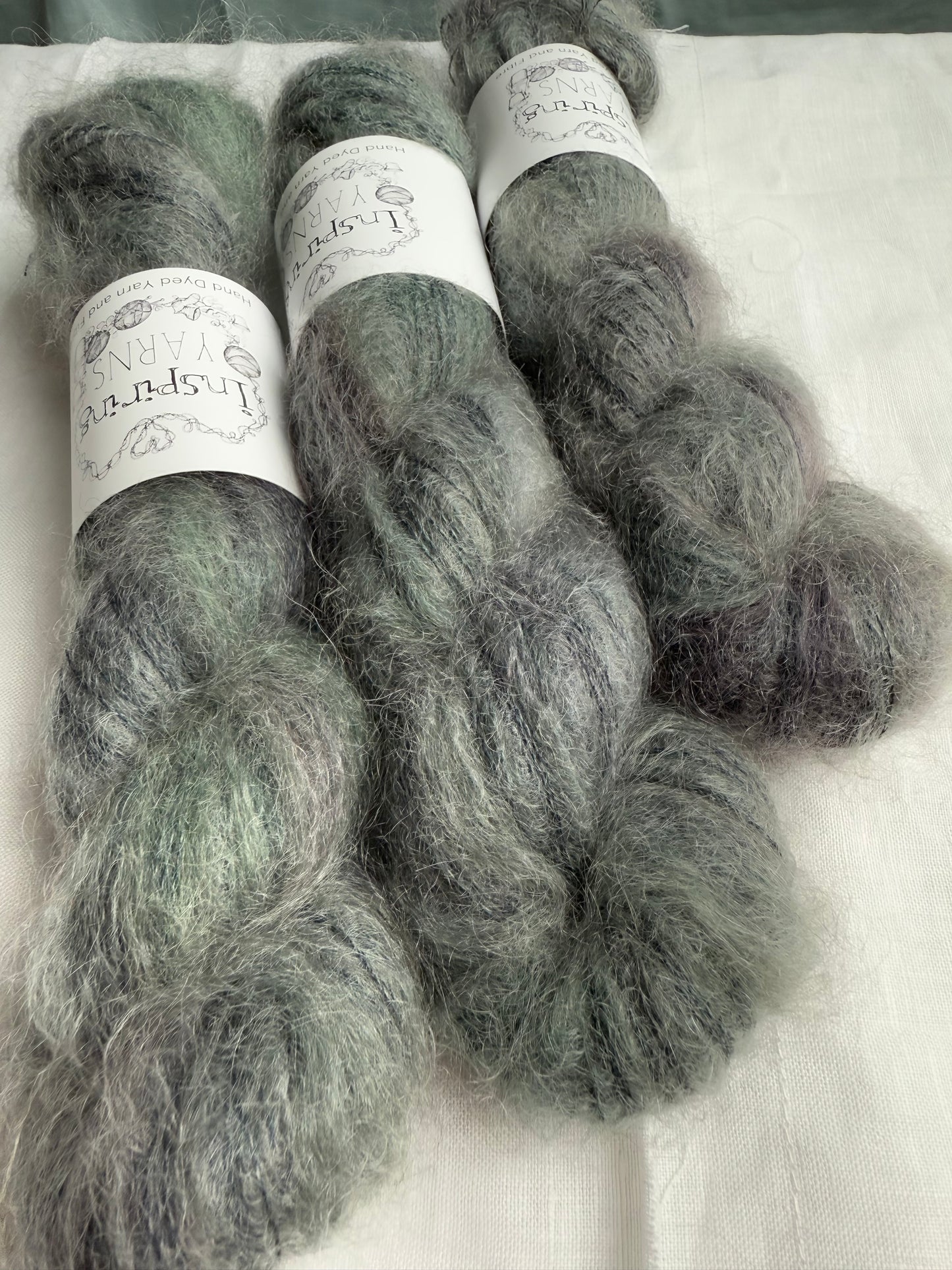 Three skeins of grey yarn with labels on a white background.