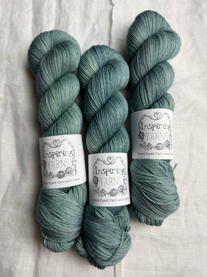 Three skeins of teal yarn with 'Inspiring Yarns' labels on a white background