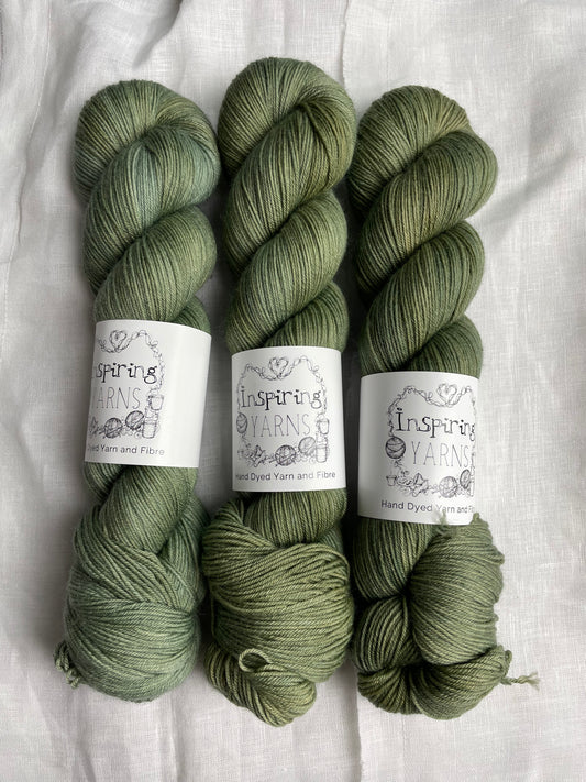 Three skeins of pale green Merino Smooth Sock yarn labelled Inspiring Yarns on a white linen background.