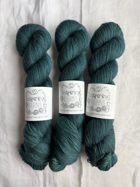 Three skeins of blue/green yarn with white inspiring yarns labels on a white background