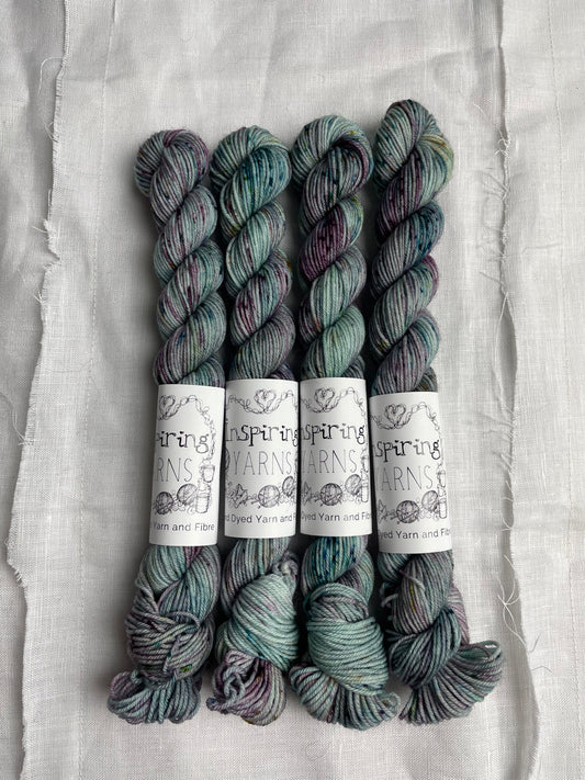 Four skeins of merino smooth sock yarn in a light teal colour with coloured speckles labelled Inspiring Yarns on a white linen background. 
