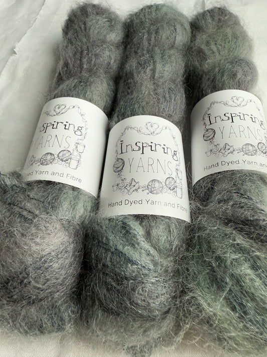 three skeins of grey yarn with green tones with white inspiring yarns labels on white background.