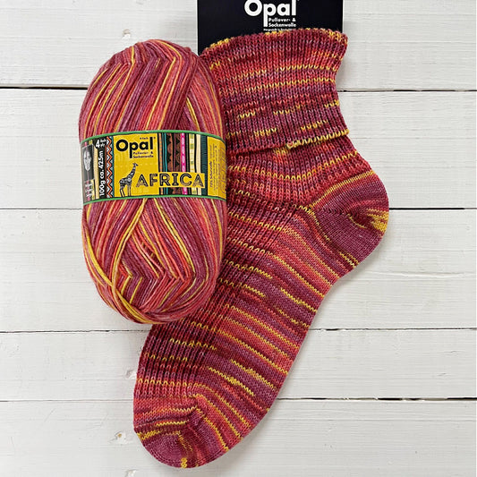 Opal Africa yarn ball and sock  in reds and yellow on a wooden surface