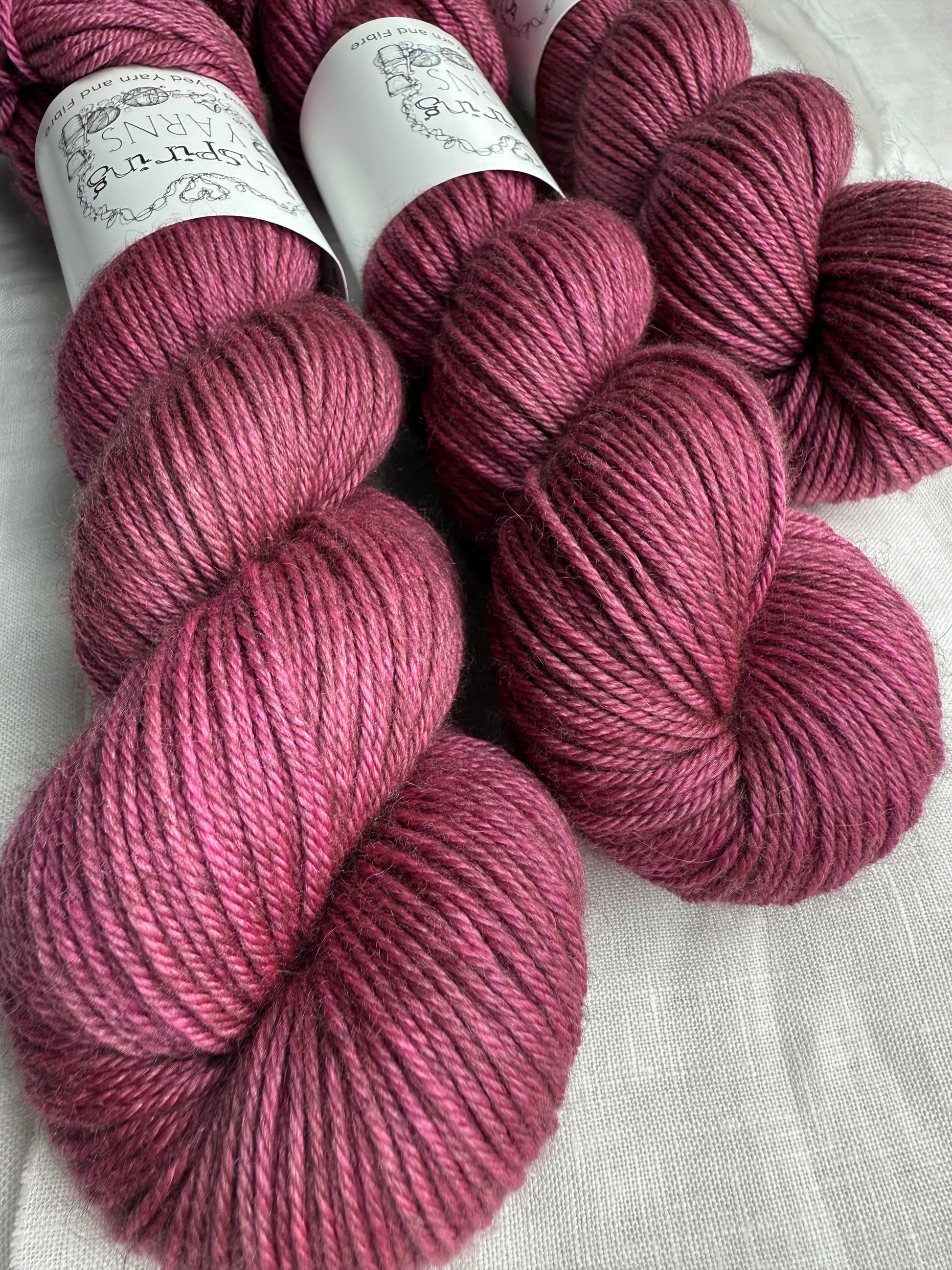 Pink yarn skeins on a white fabric background