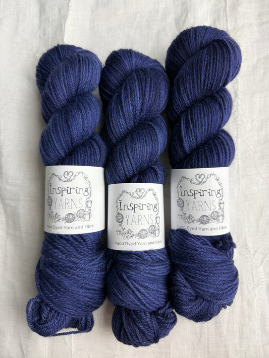 Three skeins of dark navy tonal yarn labelled Inspiring Yarns on a white background