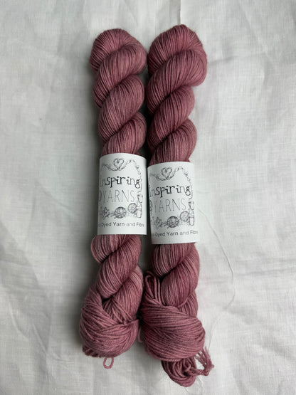 two skeins of dusty pink hand dyed yarn side by side on what background with inspiring yarns labels.
